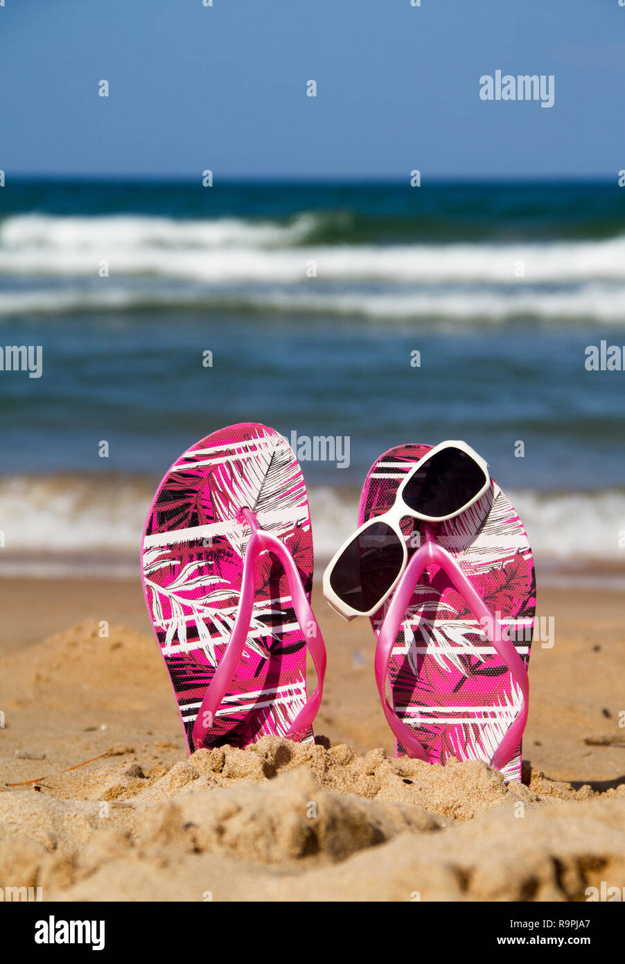 A pair of flip flops with sunglasses on the beach Stock Photo - Alamy