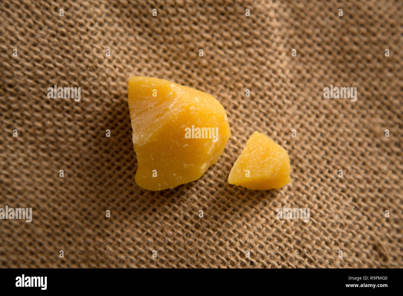 Pieces of natural bees wax on neutral jute background. Blocks of yellow wax. Stock Photo