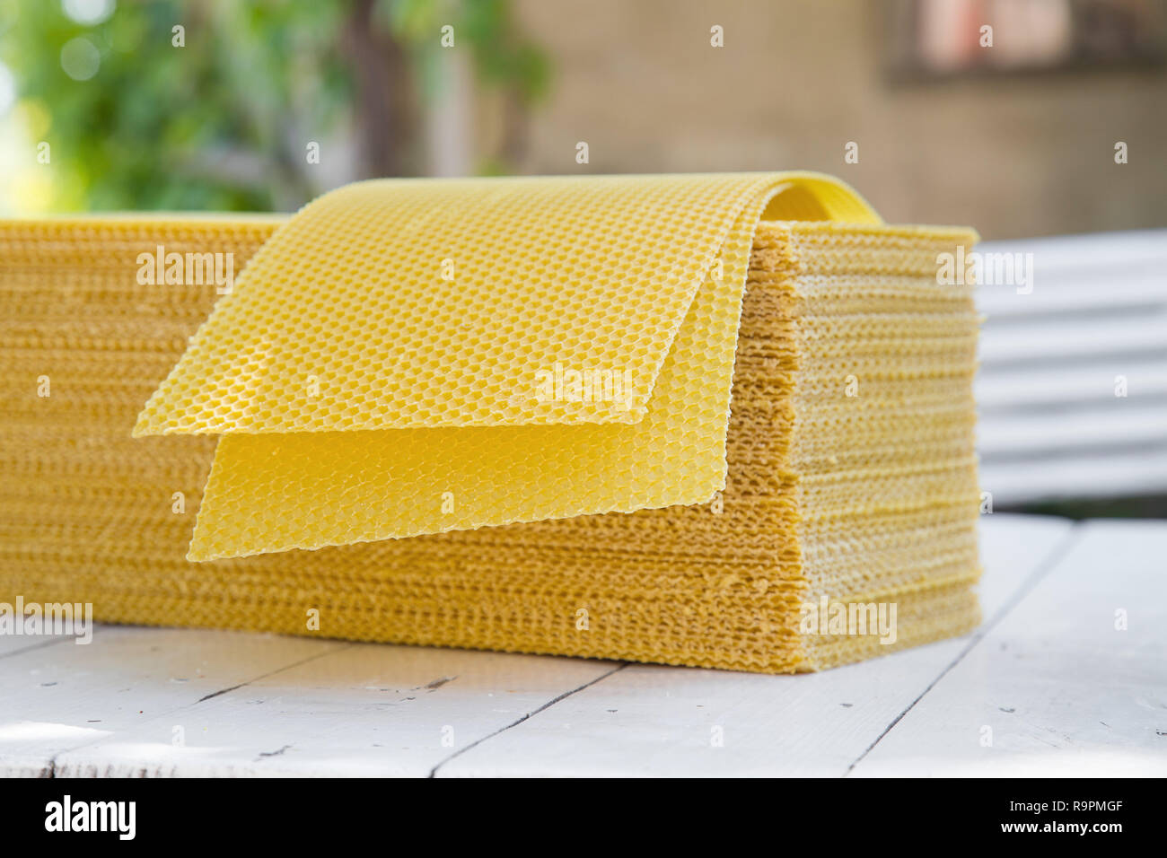 Plates of wax foundation - stack of apiary honeycomb base elements on wooden table. Image of basic beekeeping tools - wax foundation in rustic scenery Stock Photo