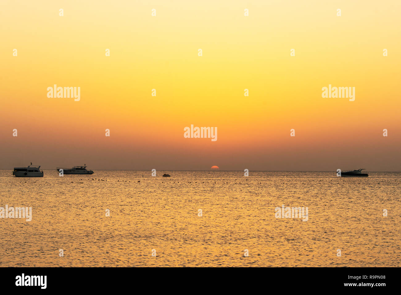 boat silhouetts on the shores of the red sea at sunset in Makadi Bay ...