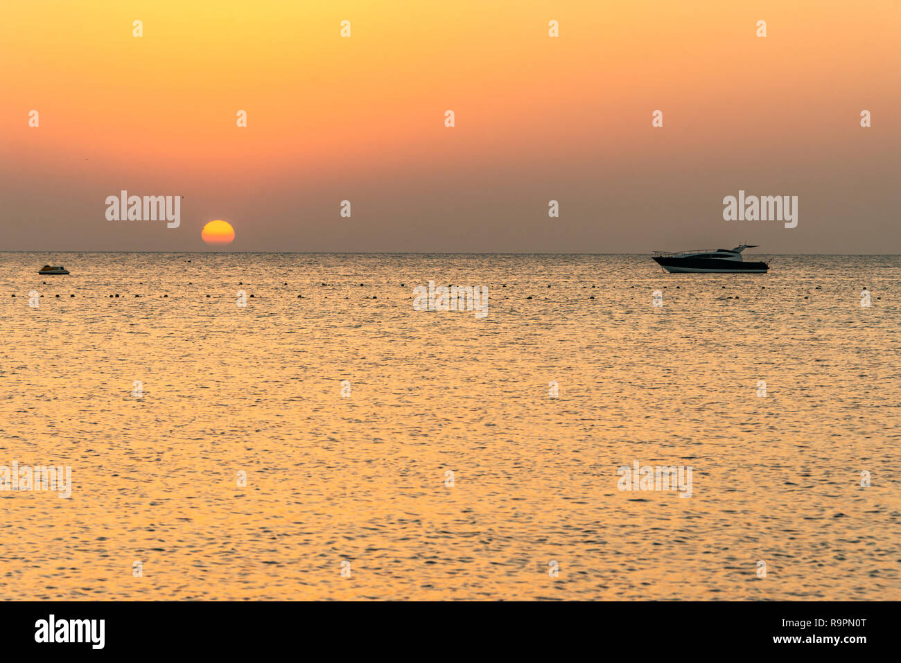 boat silhouetts on the shores of the red sea at sunset in Makadi Bay ...