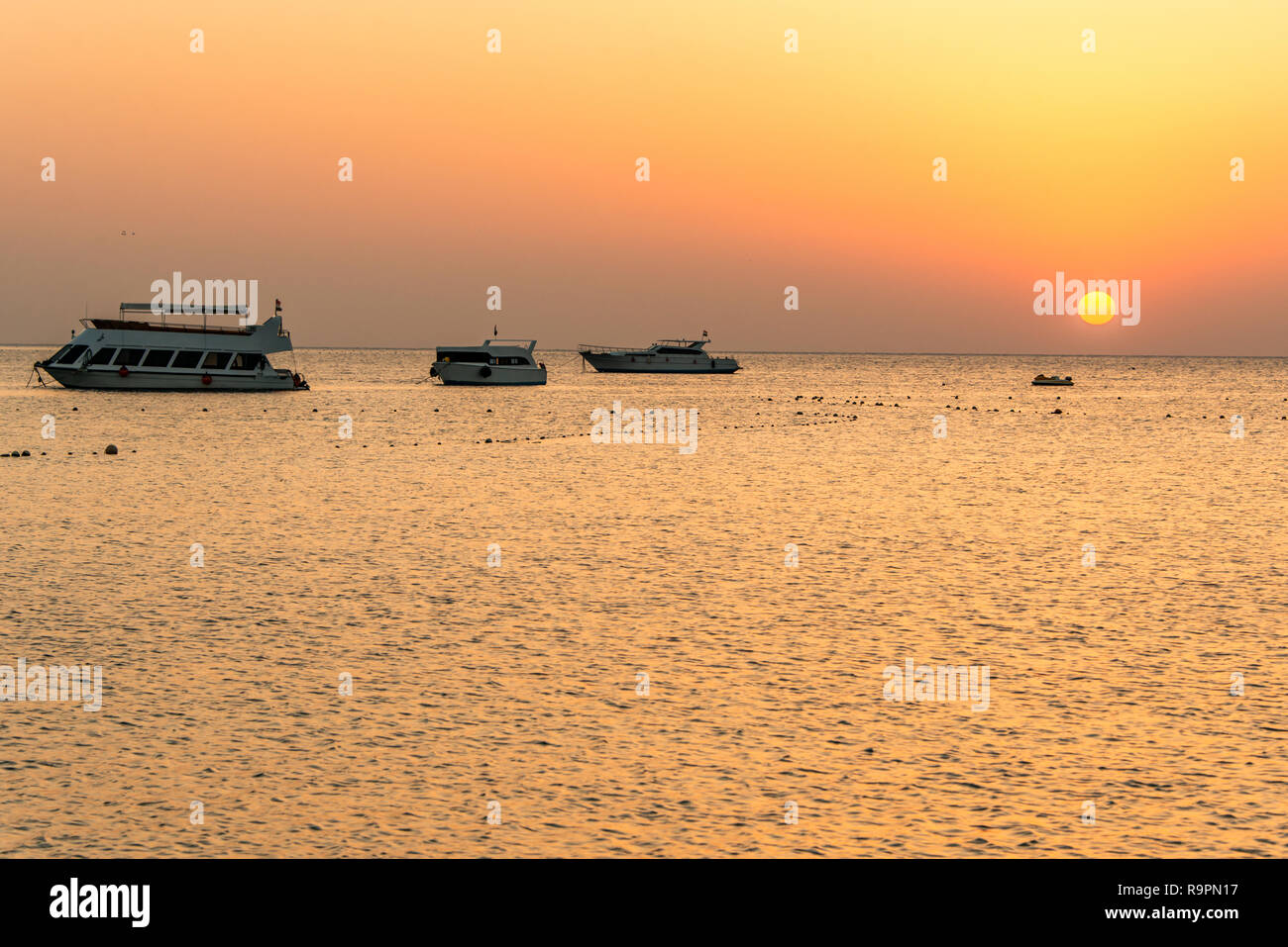 boat silhouetts on the shores of the red sea at sunset in Makadi Bay ...
