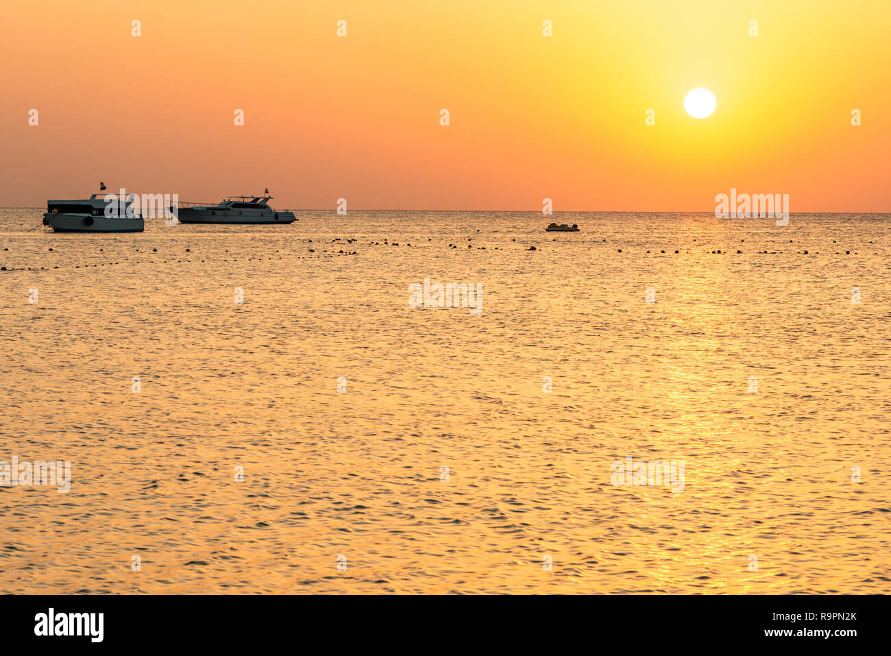 boat silhouetts on the shores of the red sea at sunset in Makadi Bay ...