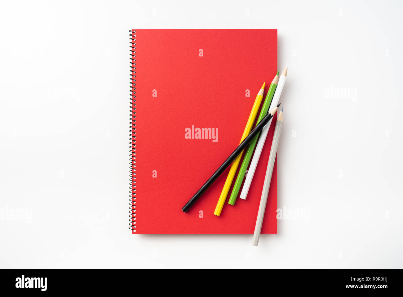 Design concept - Top view of  red spiral notebook and lot of pencils isolated on background for mockup Stock Photo