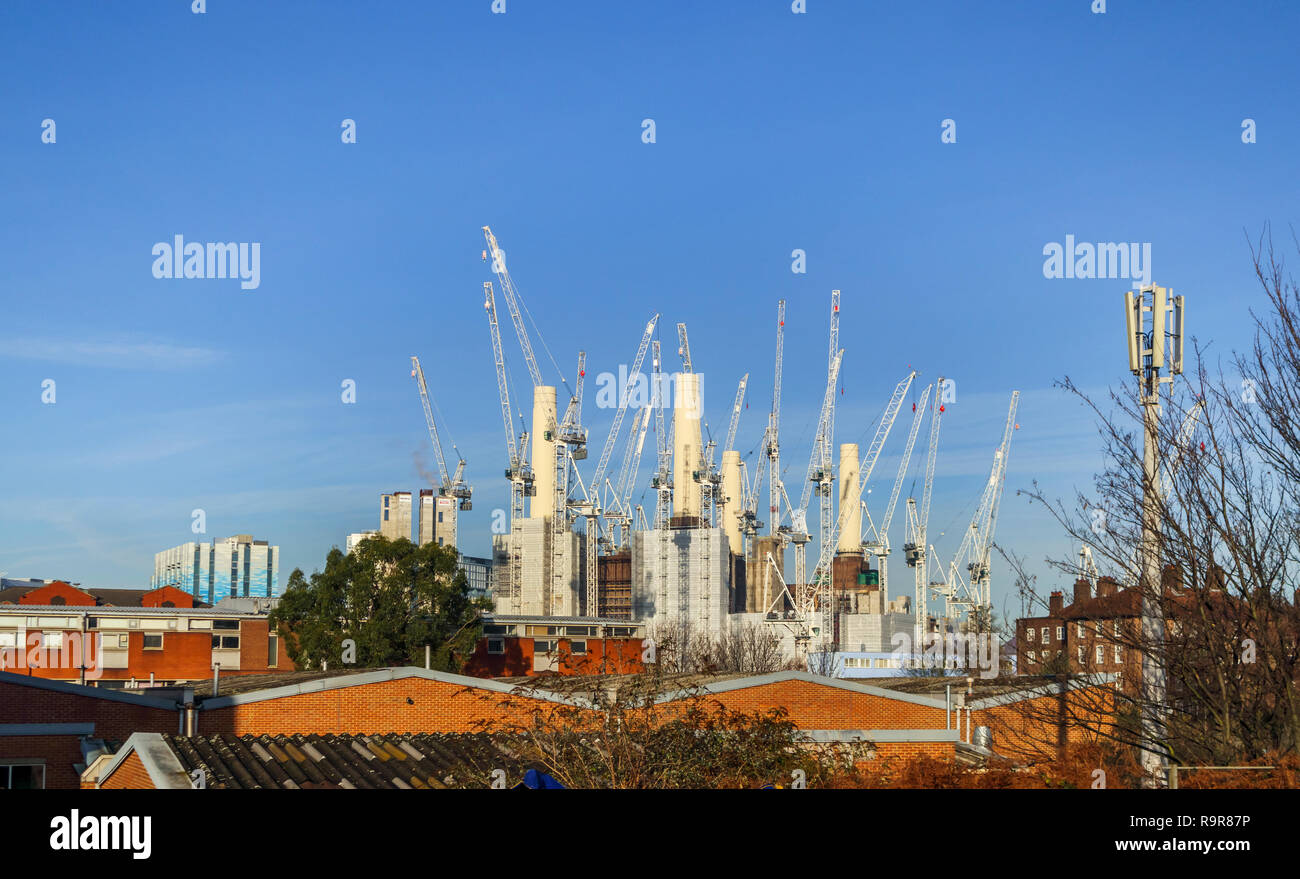 White tower cranes surround the iconic decommissioned Battersea Power Station being redeveloped for mixed uses and high class luxury apartments Stock Photo