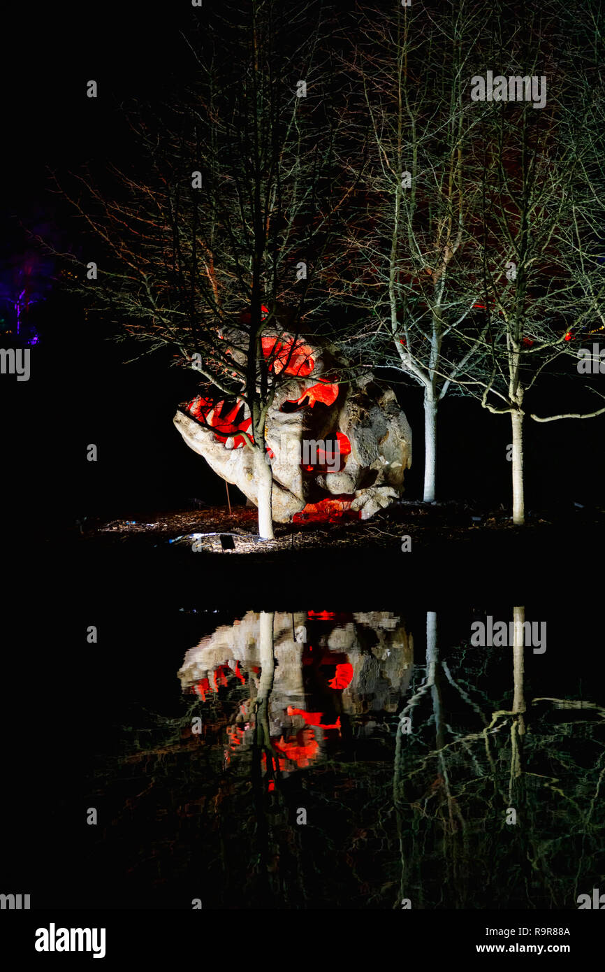 Popular 2018 Annual Wisley Glow event at the RHS Gardens, Wisley, Surrey, southeast England: sculpture of head of a T-Rex dinosaur reflected in a lake Stock Photo