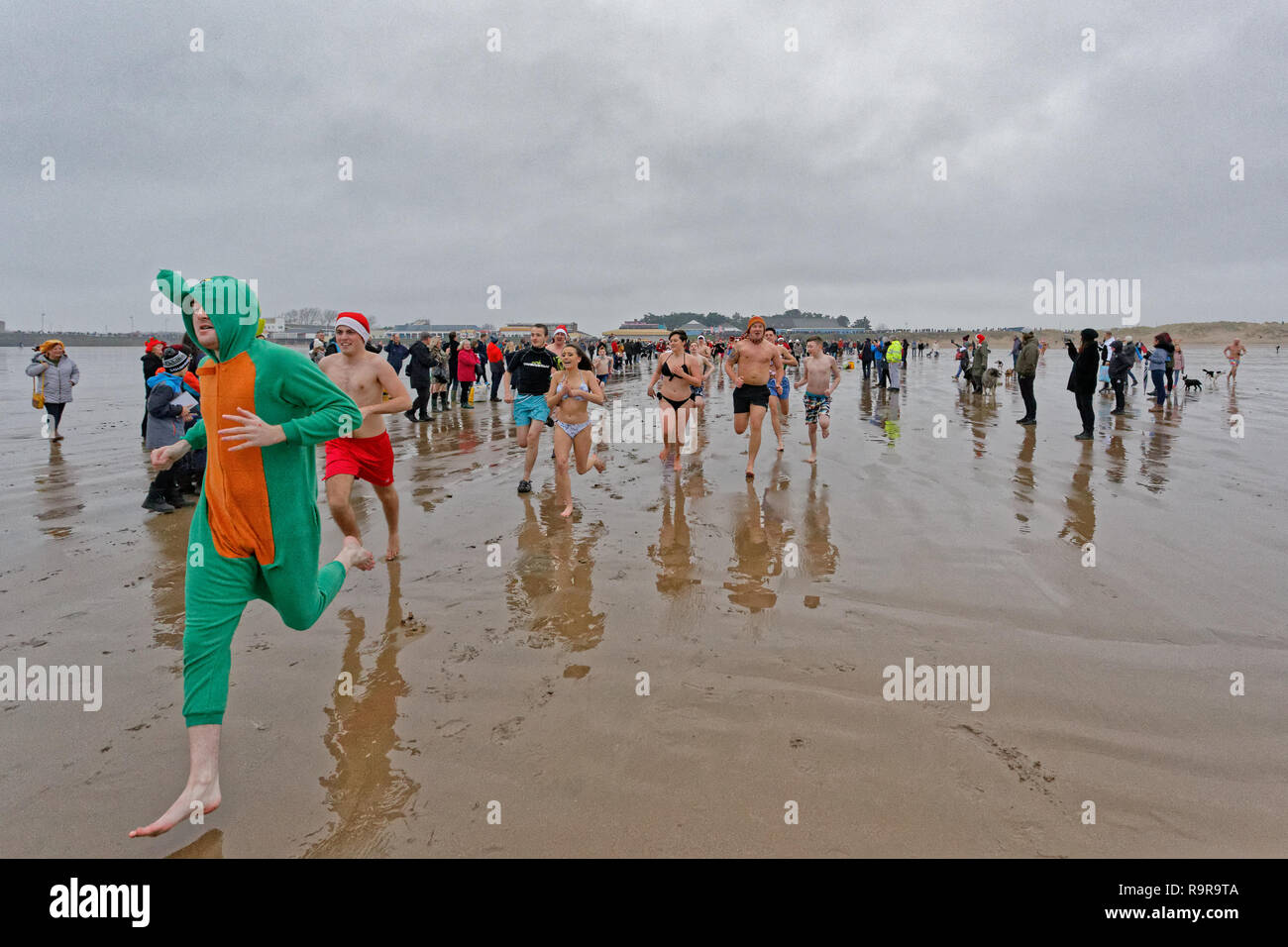 Pictured: People run to the freezing cold see. Tuesday 25 December 2018 Re: Hundreds of people take part in this year's Porthcawl Christmas Swim in so Stock Photo