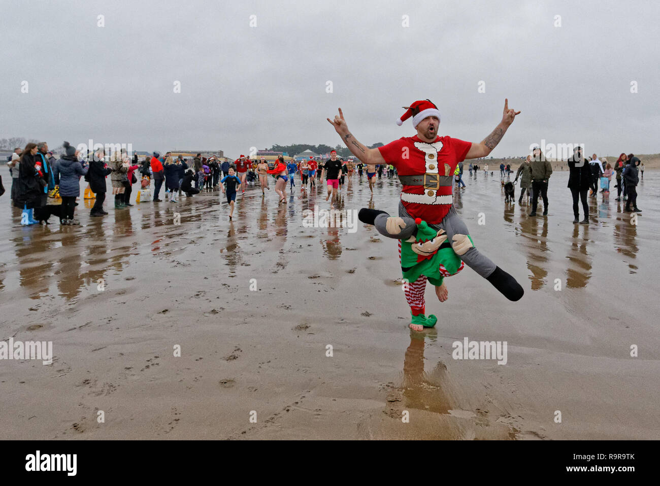 Pictured: A man in an elf fancy dress costume runs to the freezing cold see. Tuesday 25 December 2018 Re: Hundreds of people take part in this year's  Stock Photo