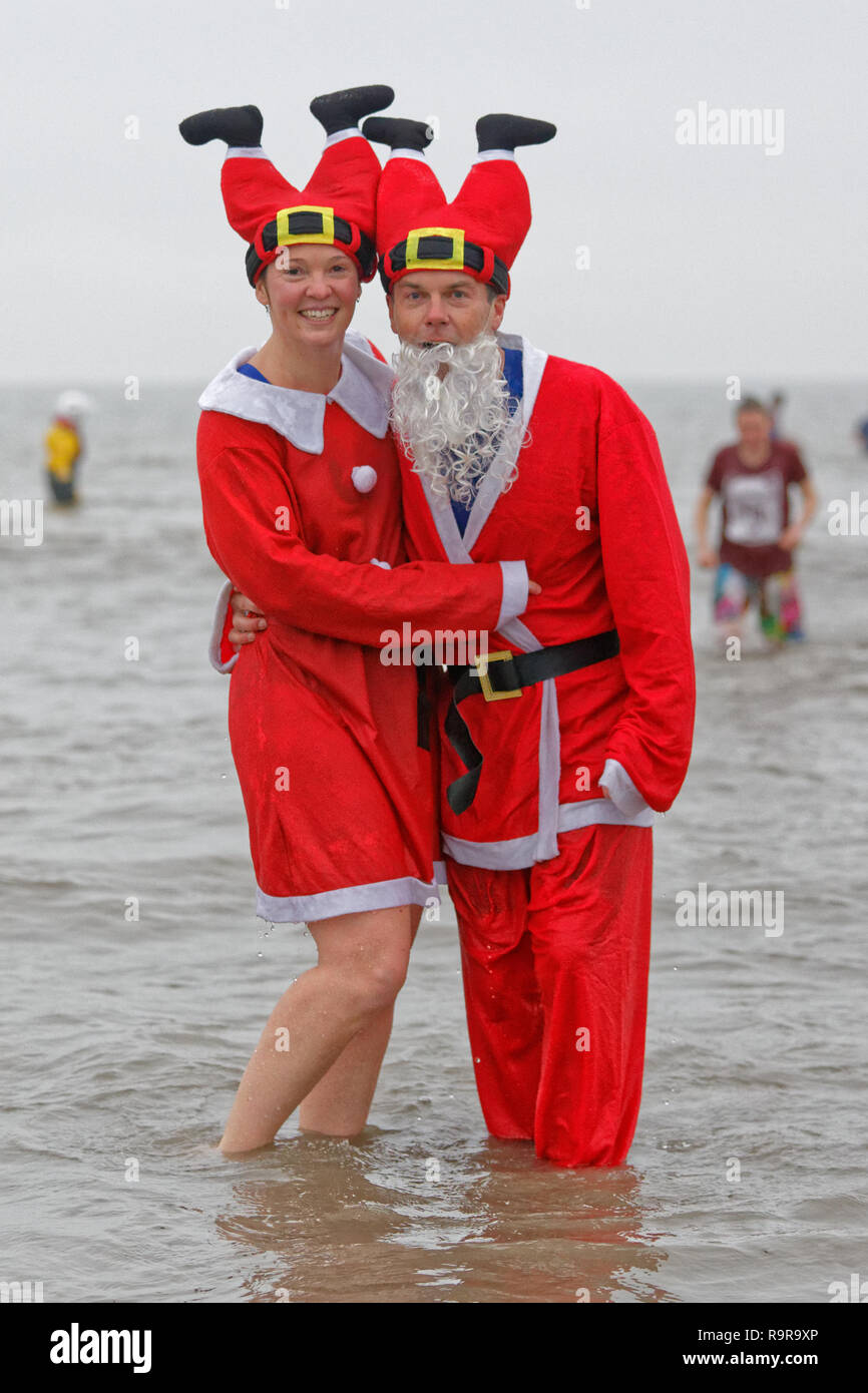 Pictured: A couple in Santa costumes. Tuesday 25 December 2018 Re: Hundreds of people take part in this year's Porthcawl Christmas Swim in south Wales Stock Photo
