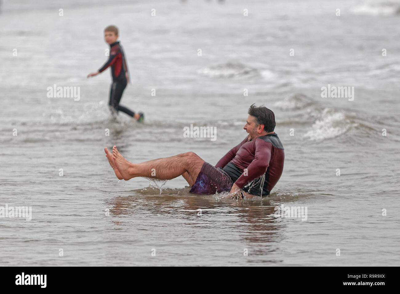 Pictured: A man attempts to get back onto his feet. Tuesday 25 December 2018 Re: Hundreds of people take part in this year's Porthcawl Christmas Swim  Stock Photo