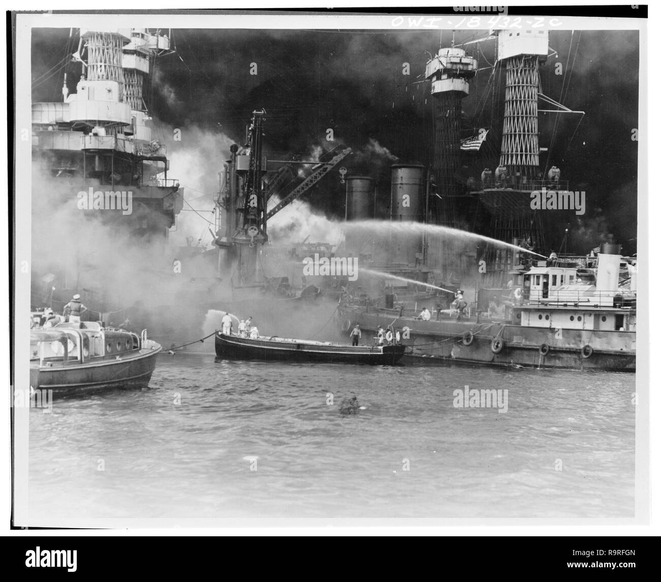 USS West Virginia aflame. Disregarding the dangerous possibilities of explosions, United States sailors man their boats at the side of the burning battleship, USS West Virginia, to better fight the flames started by Japanese torpedoes and bombs. Note the national colors flying against the smoke-blackened sky. Japanese aerial attack on Pearl Harbor, Hawaii, December 7, 1941. (Library of Congress-Farm Security Administration - Office of War Information) Stock Photo