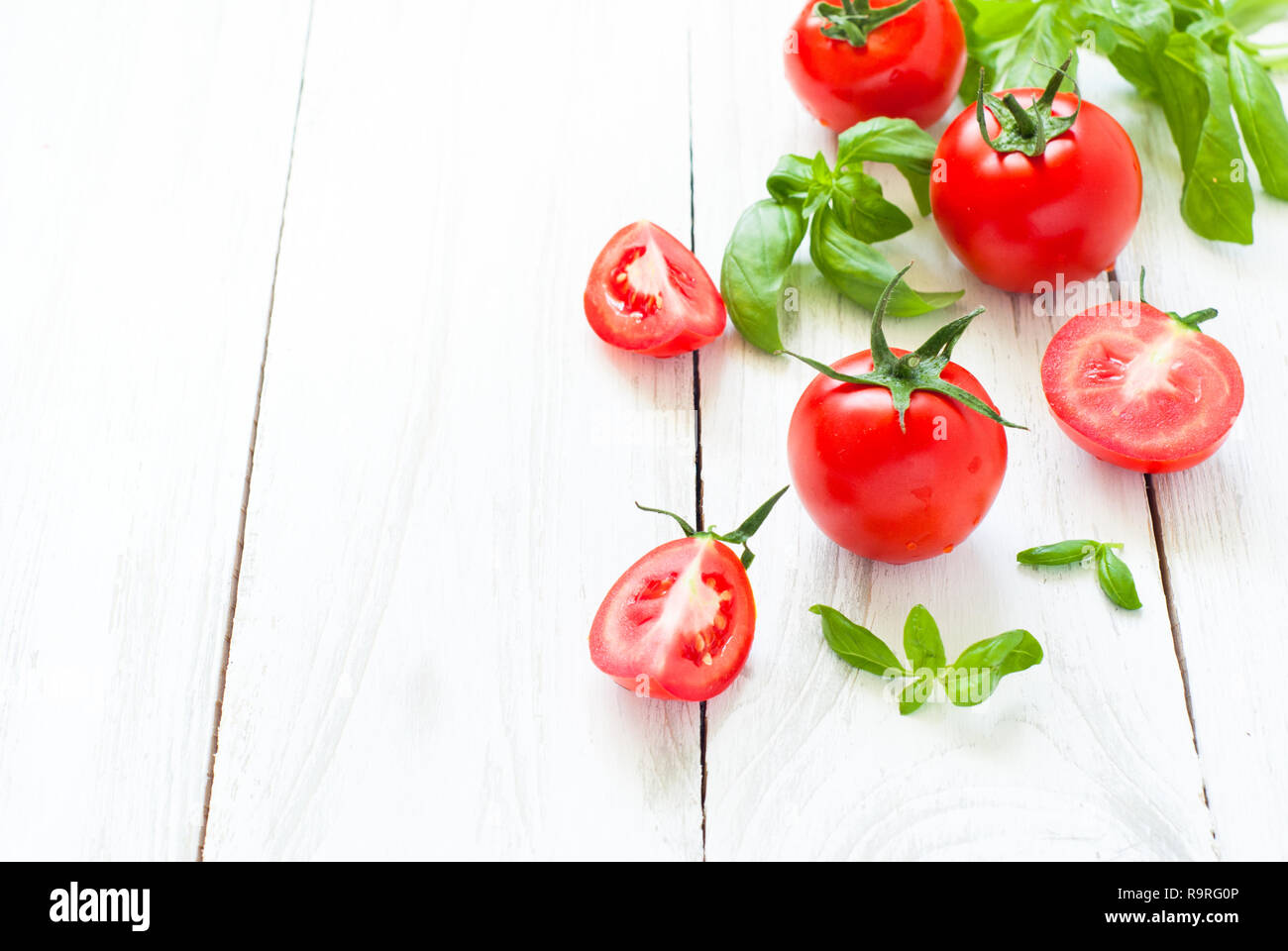 Vegetables background. Tomatoes, basil and garlic on white wooden table ...