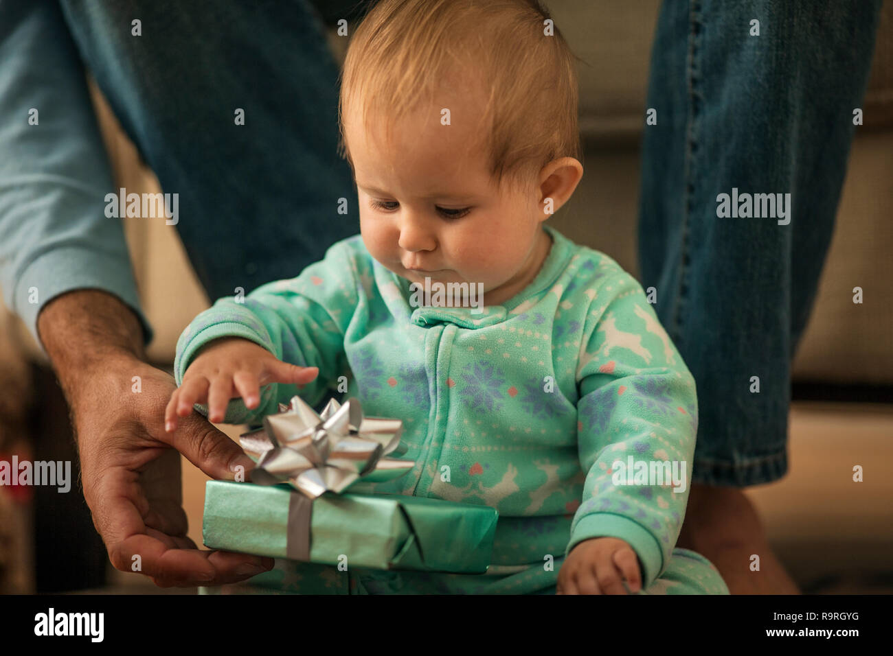 Baby girl opening a present from her father. Stock Photo