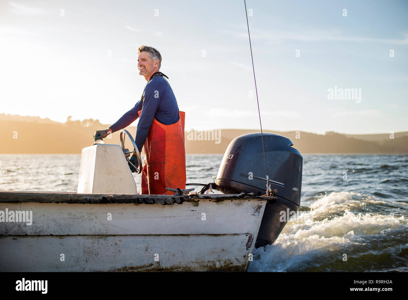 Mid adult man operating fishing boat. Stock Photo