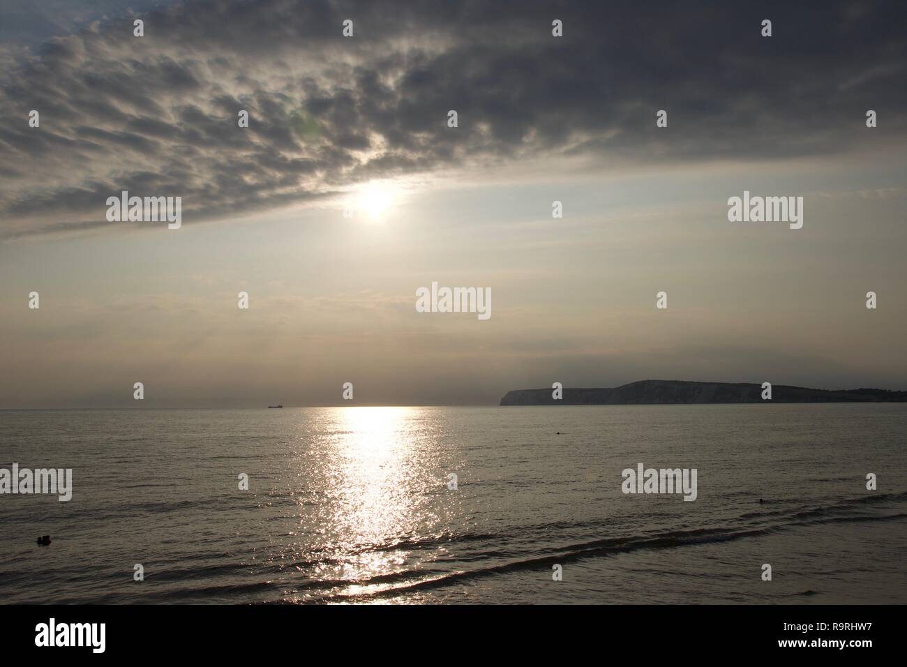 Evening on the south coast of England; yellow sun brightly reflected on the water with the famous white cliffs silhouetted in the background Stock Photo