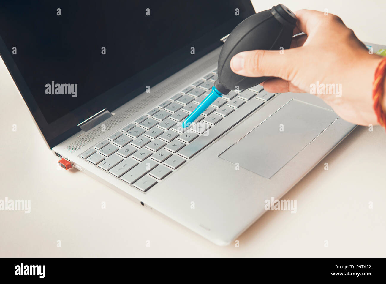Closeup shot of female hand sweeping dust from laptop keyboard using
