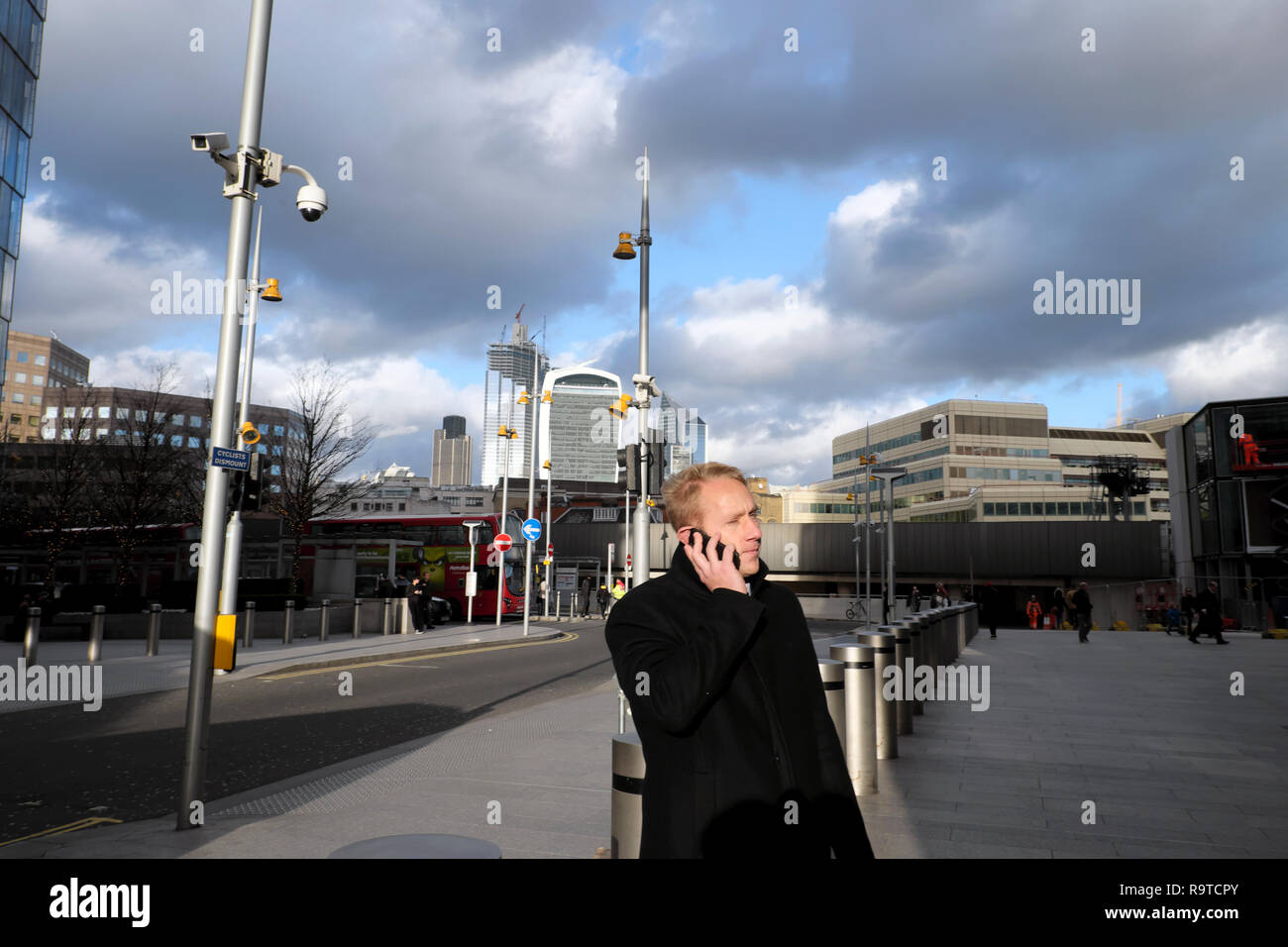 A man standing on the street near the Shard skyscraper talking on a mobile phone (cell phone) with a view of the City of London UK KATHY DEWITT Stock Photo