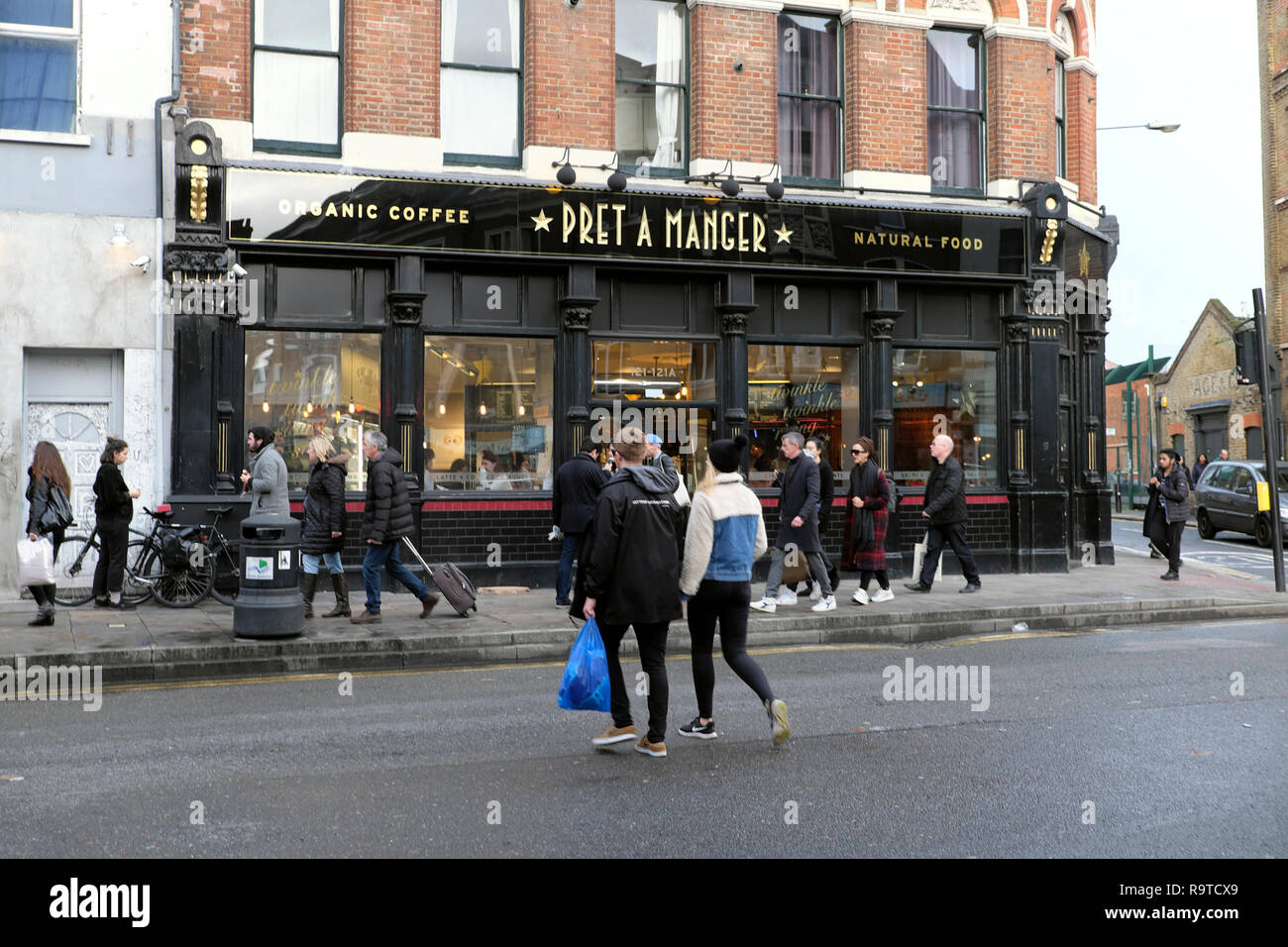Exterior street view of pedestrians crossing the road outside Pret a Manger Shoreditch East London E2 England UK KATHY DEWITT Stock Photo