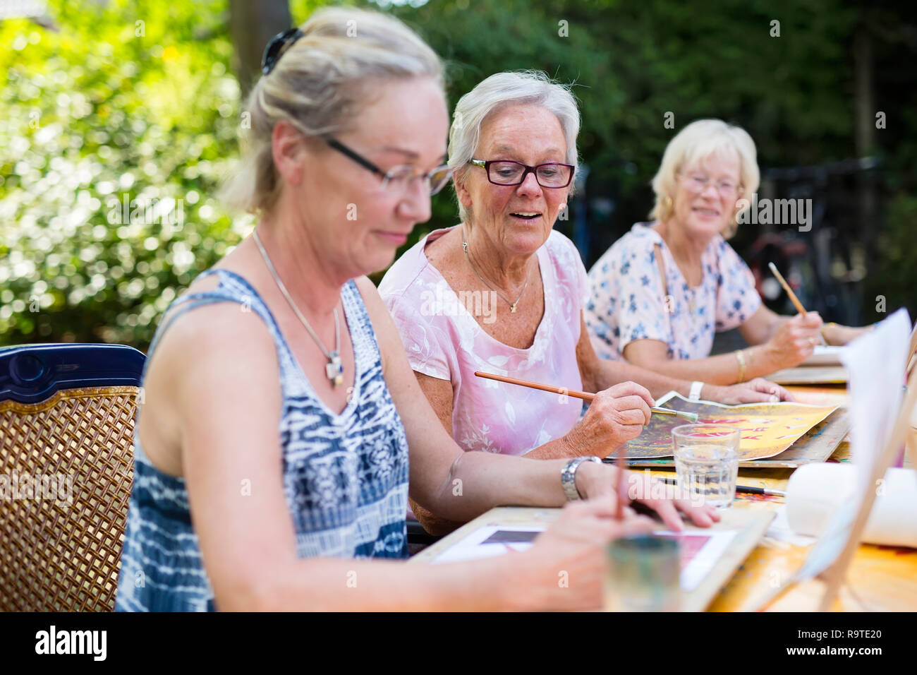 Retired senior women painting together outdoors as group recreational