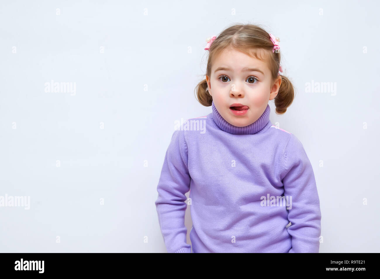 Fun surprising little girl with open mouth and big eyes looking on empty copy space Stock Photo