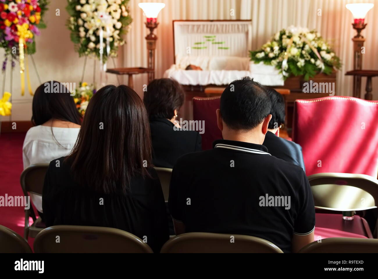 New York, NY USA. Jun 2016. Catholic Asian American friends and family sitting in silence praying and paying respects to their loved one. Stock Photo