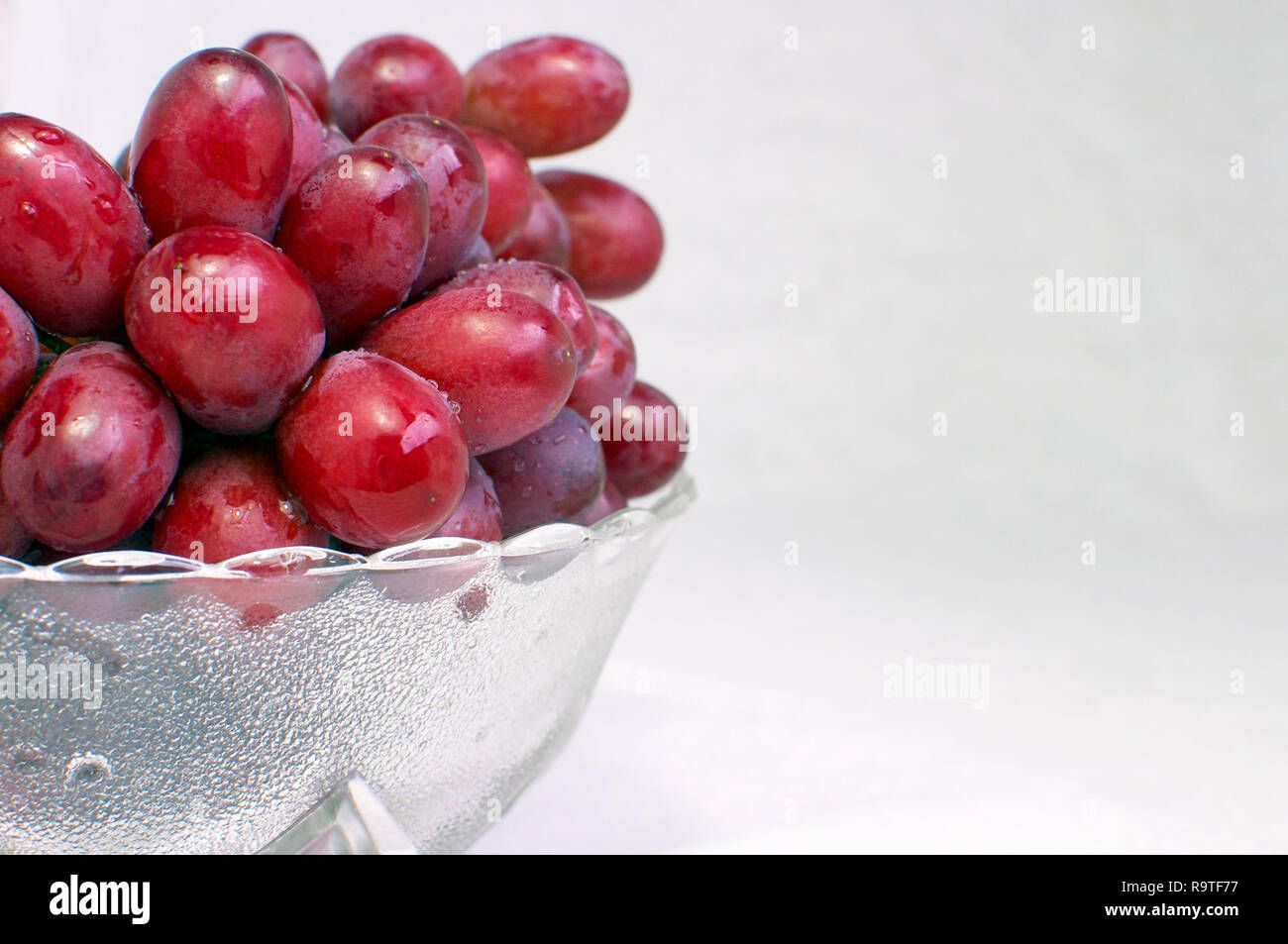 Bunch of Seedless Red Grapes (Vitis vinifera) in a Glass Bowl Offset Stock Photo