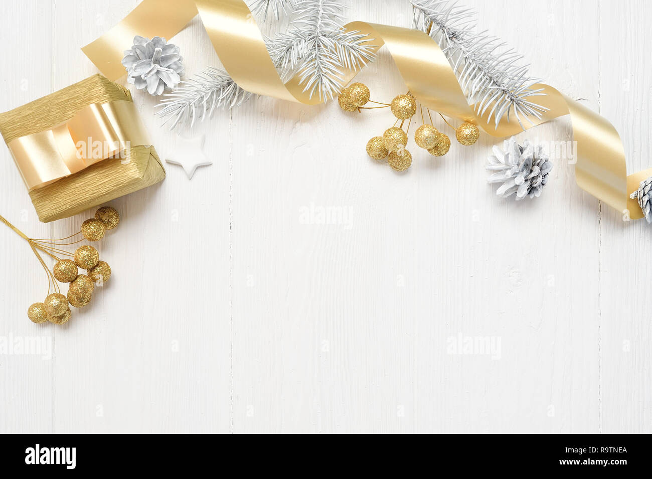 Mockup Christmas white tree, beige bow, gold gift box and cone. Flat lay on a white wooden background, with place for your text. Top view Stock Photo