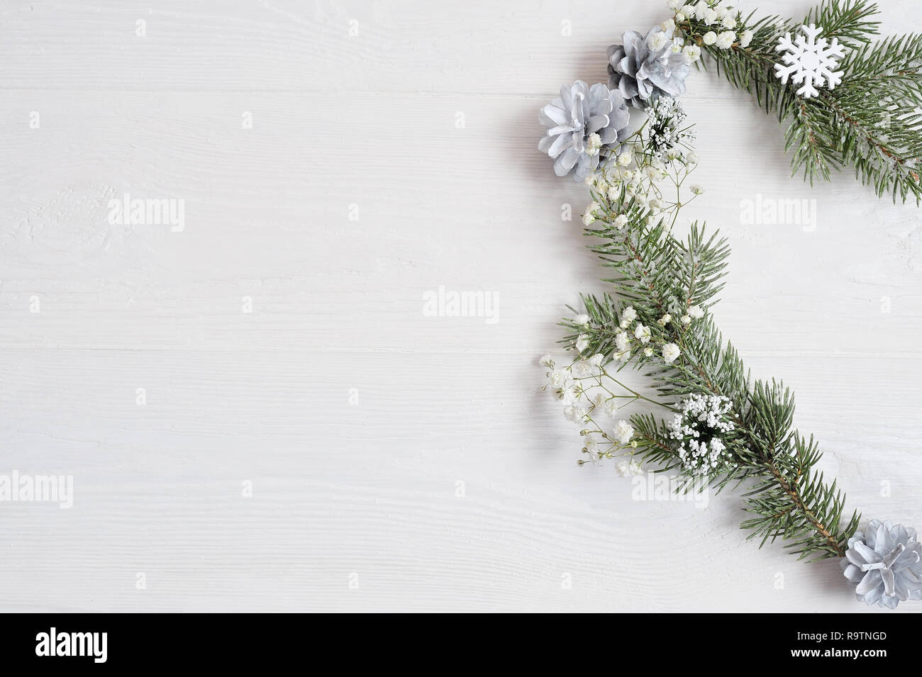 Mockup of Christmas Wreath in form of heart Decorated with white snowflakes and cones. On white wooden background Stock Photo