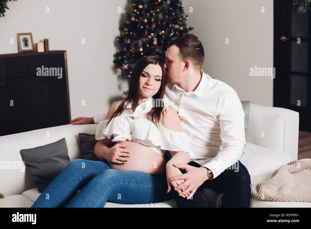 Happy Husband And Wife Sitting On White Sofa With Plaids And