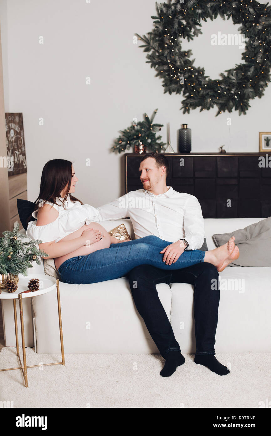 Happy Husband And Wife Sitting On White Sofa With Plaids And