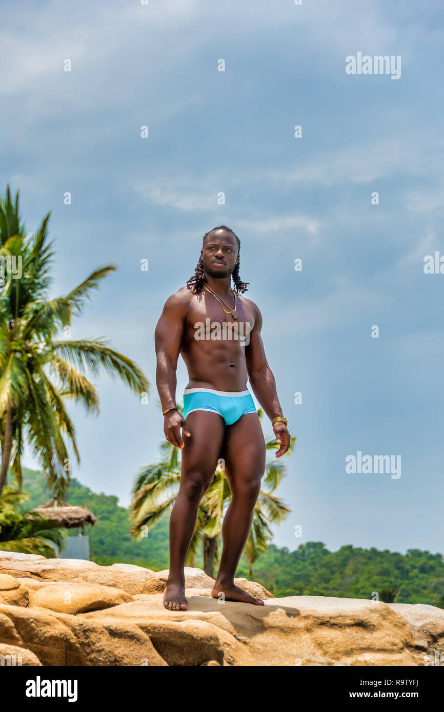 Young, handsome, muscular, shirtless African American man standing on the rock on Yelapa beach near Puerto Vallarta, Mexico. Stock Photo
