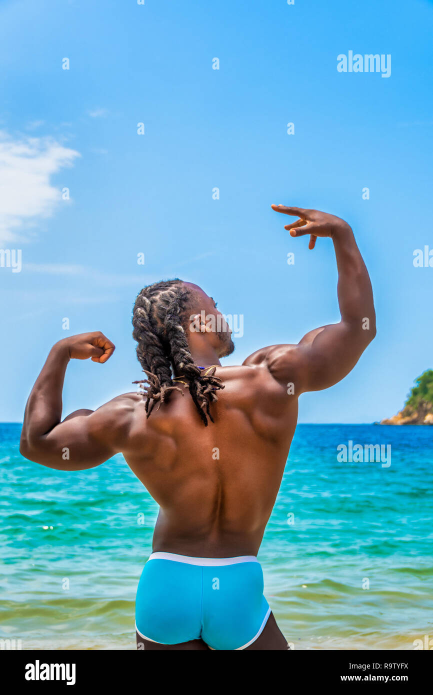 Young, handsome, muscular, shirtless African American man, posing in the water showing his back, on Yelapa beach near Puerto Vallarta, Mexico. Stock Photo