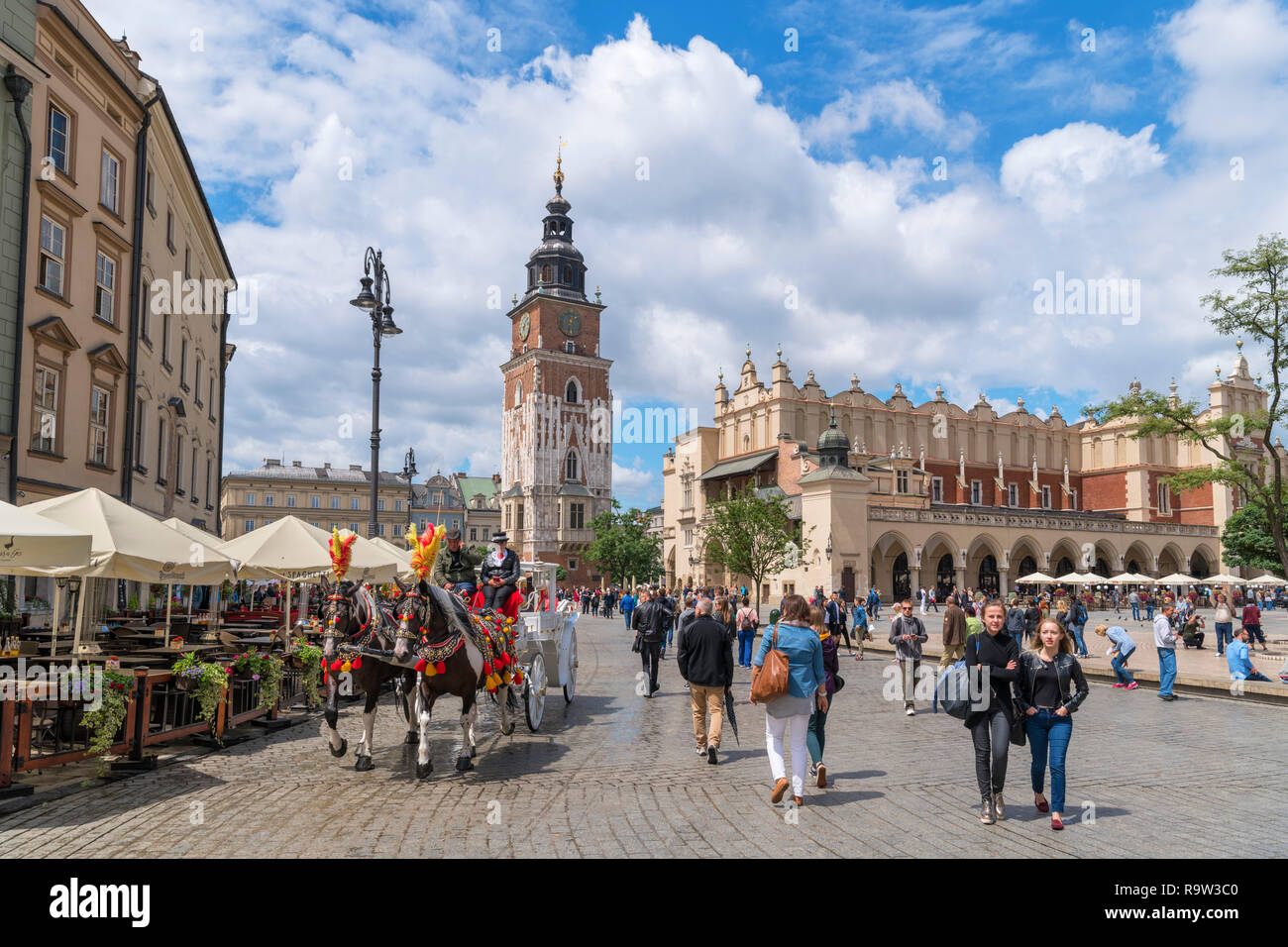 Horse and Carriage ride in front of the Town Hall Tower (Wieża ratuszowa) & Cloth Hall (Sukiennice) in the Main Square (Rynek Główny), Kraków, Poland Stock Photo