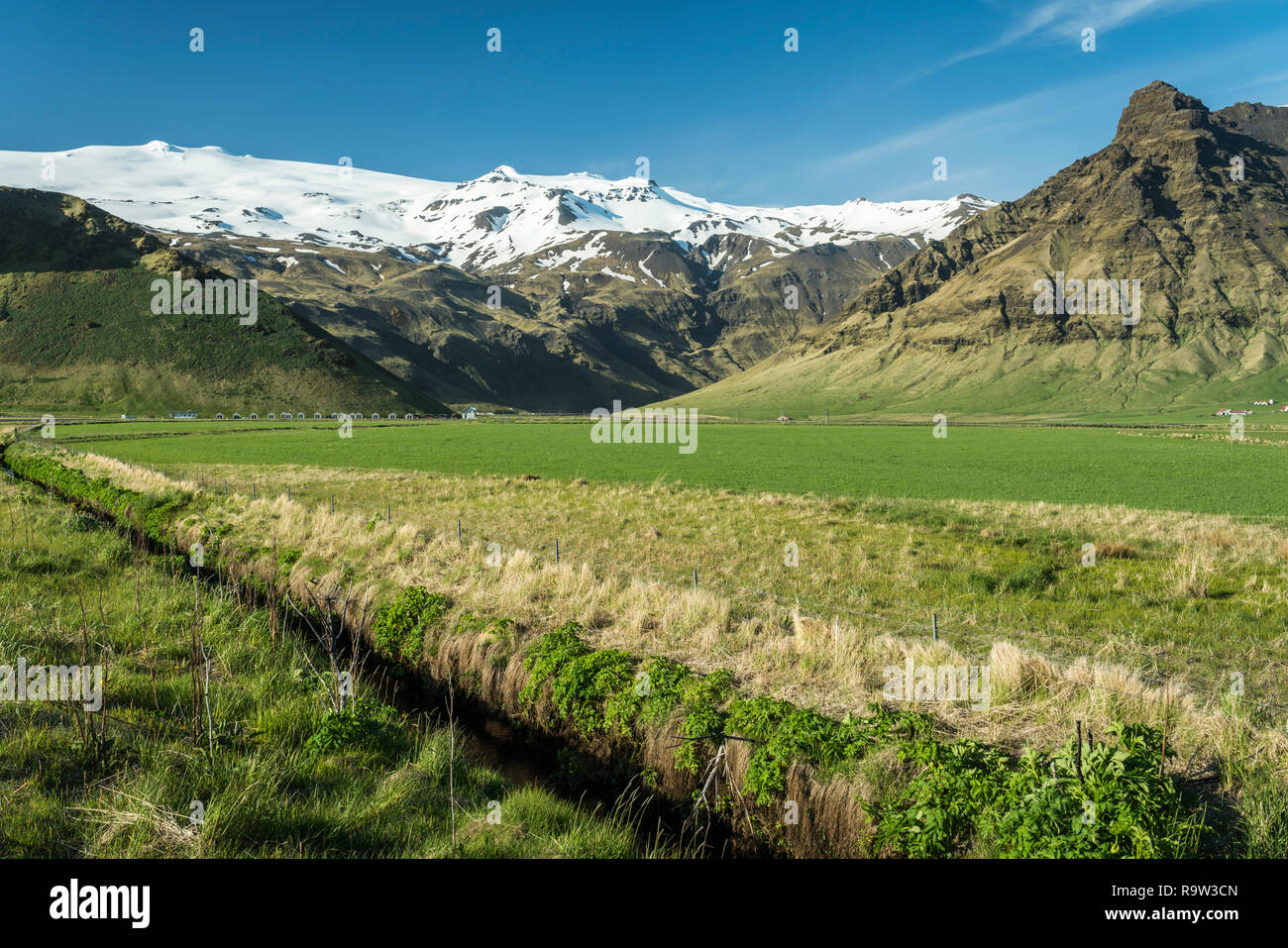 A Green Meadow Drainage Canal And Snow Capped Mountain Range In Southern Iceland Europe Stock Photo Alamy