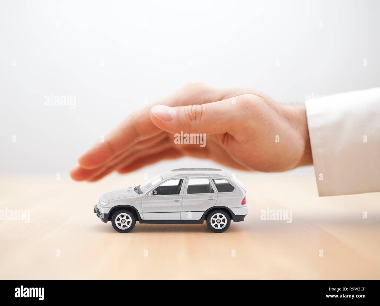 Car insurance. Small silver car covered by hand. Stock Photo