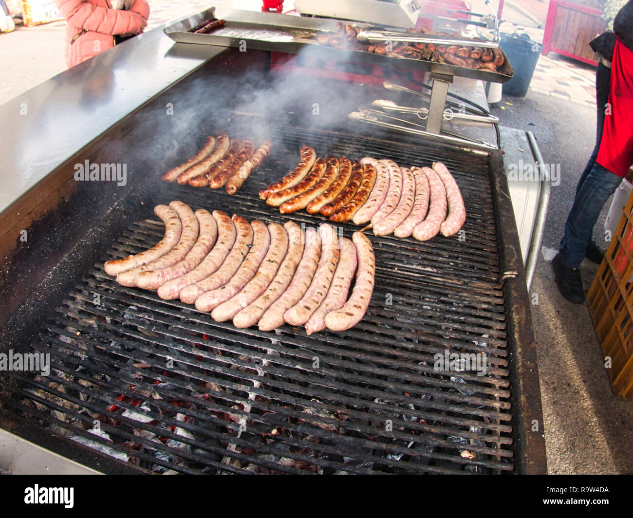 Frying fresh meat barbecue sausages merguez brats, BBQ picnic sandwich store outdoor on big grill Stock Photo