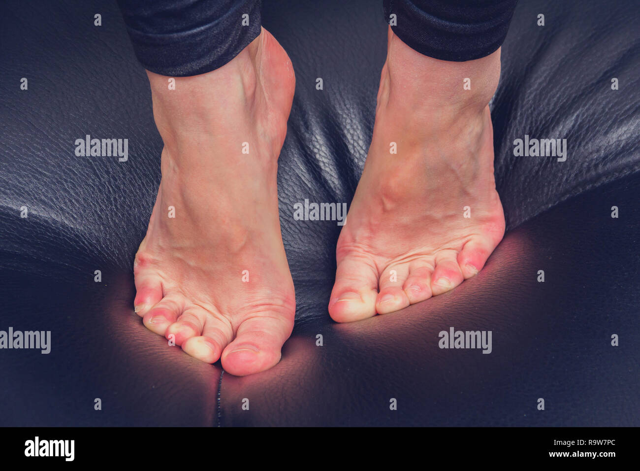 Legs and feet of woman close up on black leather sofa Stock Photo Alamy