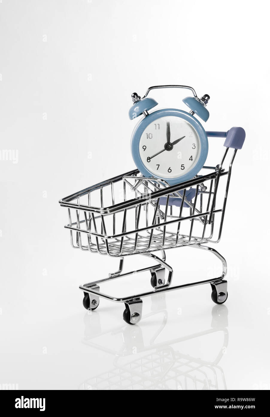 Alarm clock in a shopping trolley on a white background. Stock Photo