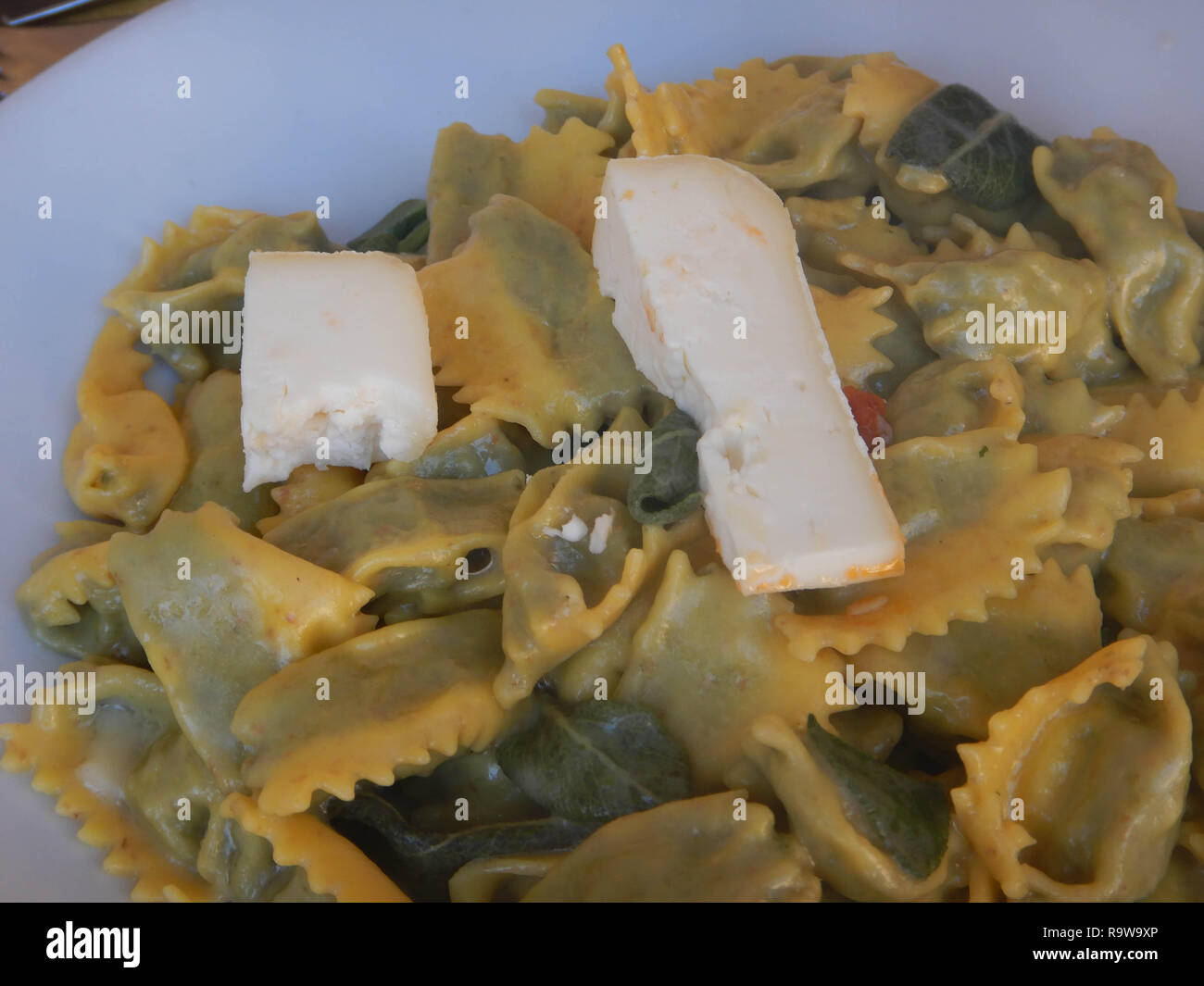 A dish of agnolotti with butter and sage in a dish with grated cheese   and two pieces of tuma ready to be eaten Stock Photo