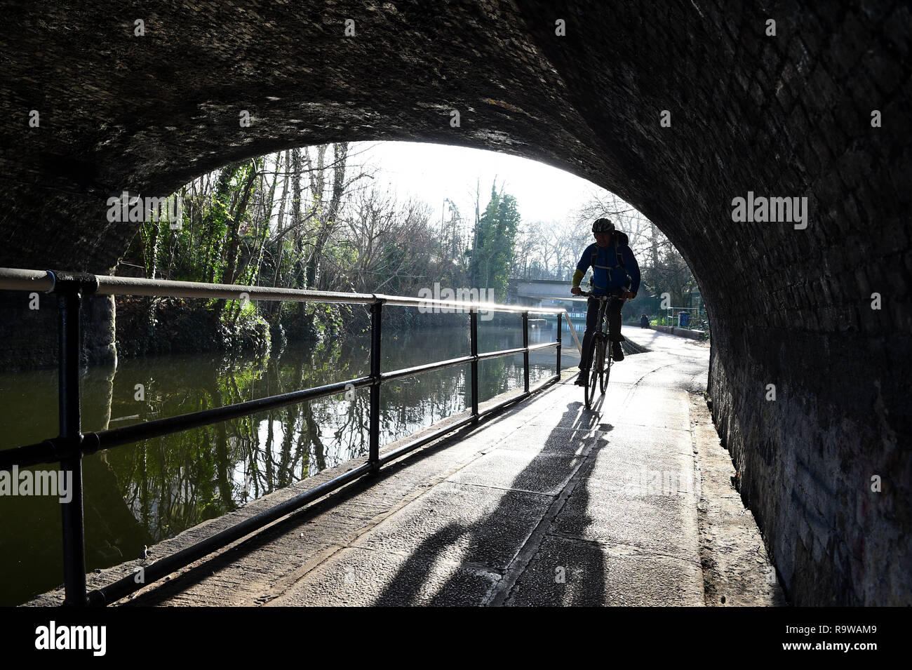 A man cycles along the towpath alongside the Regent's Canal in Camden, north London. Stock Photo
