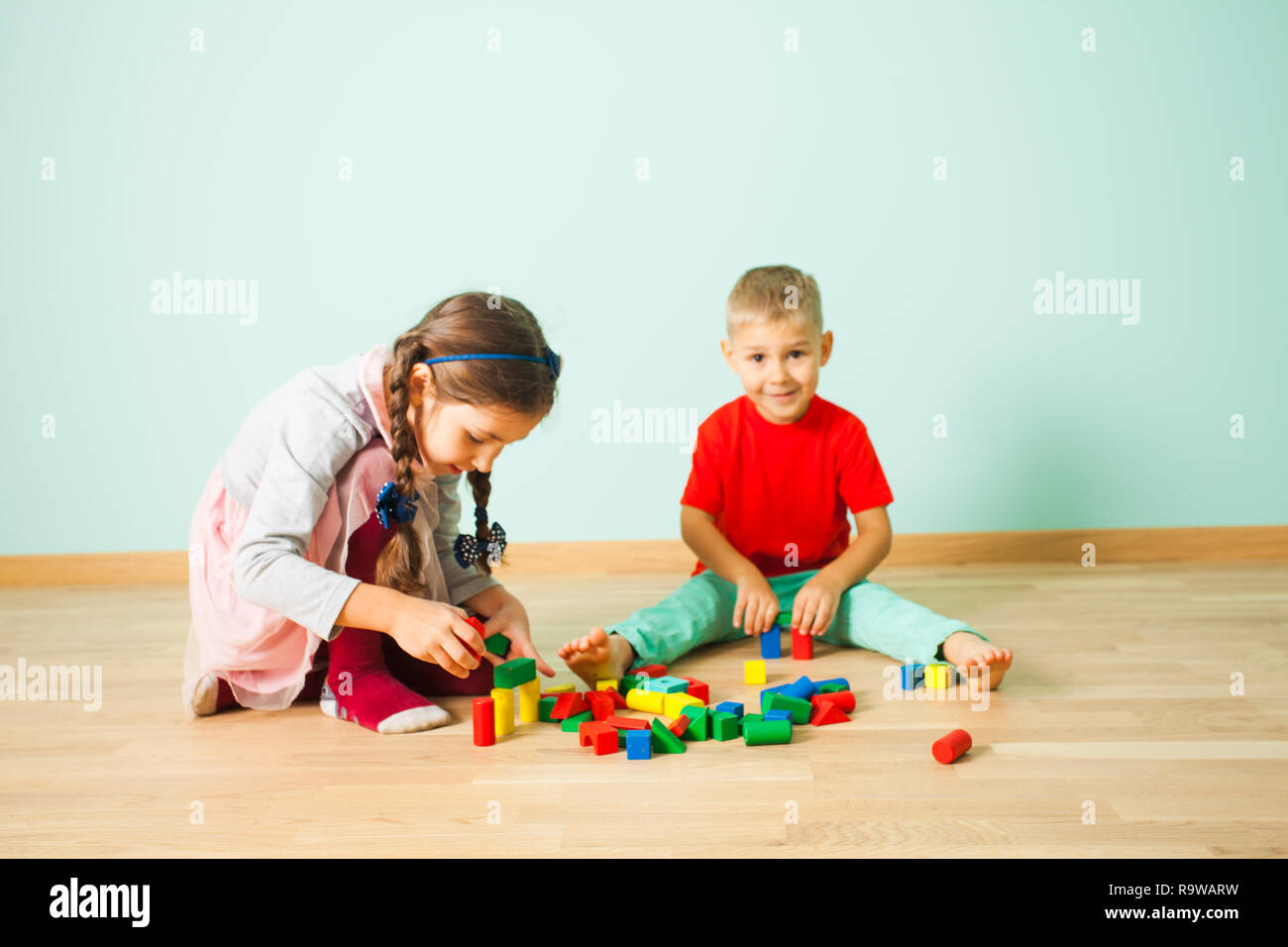 Two kids playing with wooden blocks at home Stock Photo - Alamy