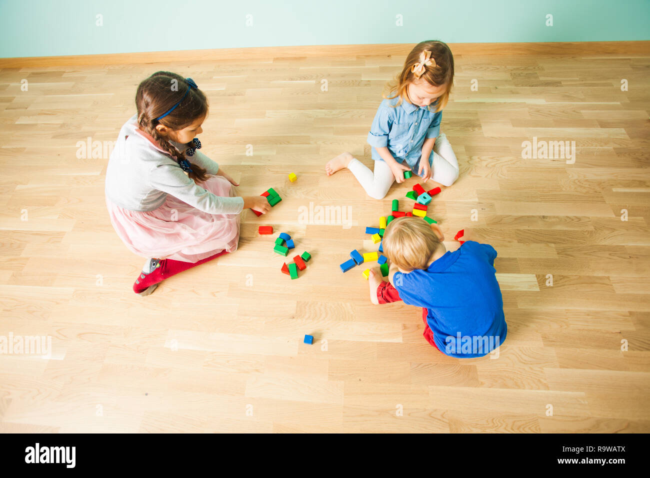 Three kids playing with wooden blocks in their room Stock Photo - Alamy