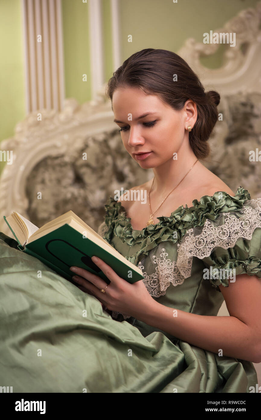 Portrait of retro baroque fashion woman wearing green vintage dress at old palace interior Stock Photo