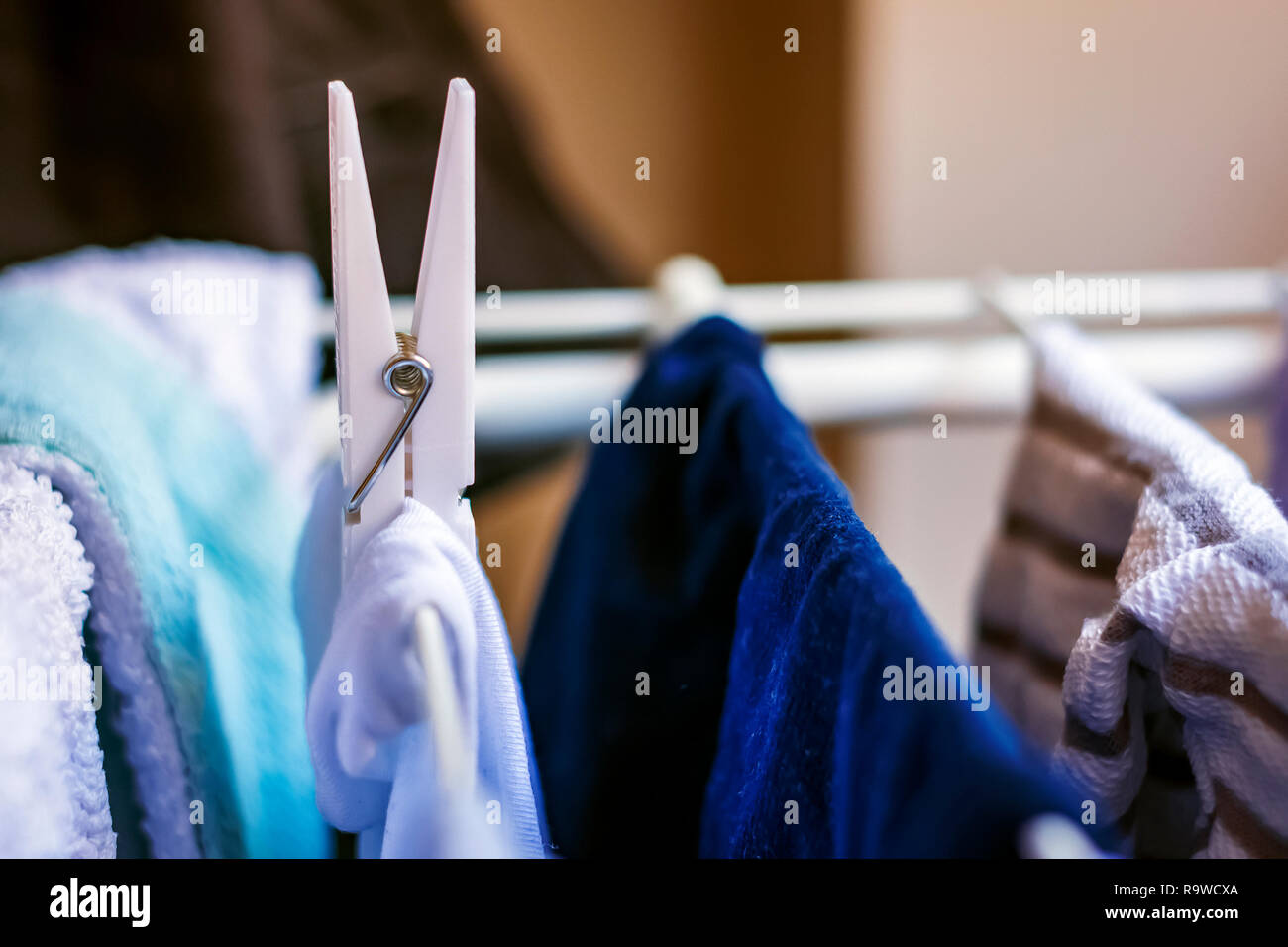 a white clothespin hangs a clothes hanging on a drying rack. Drying laundry Stock Photo