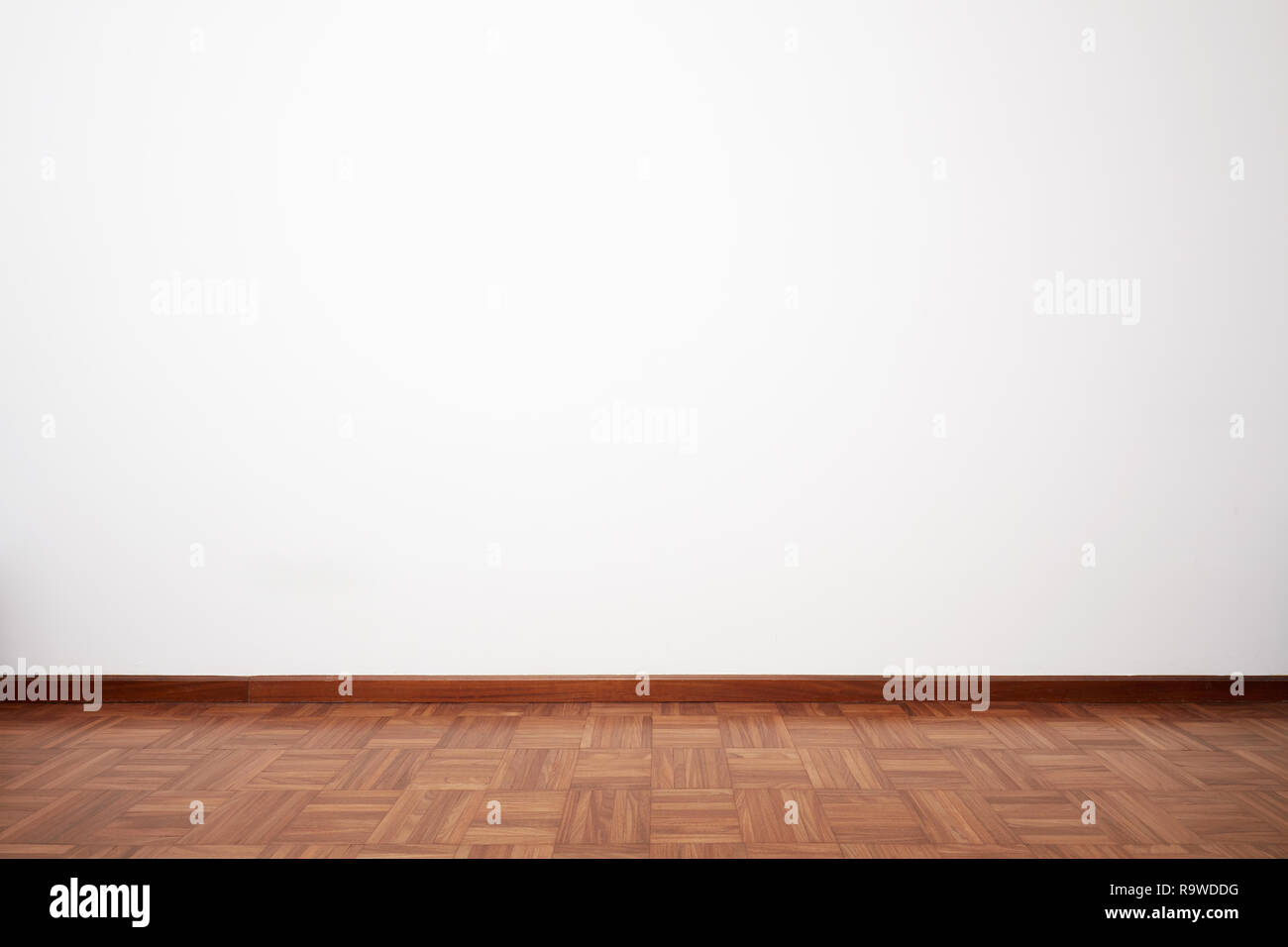 Empty room with brown wooden tiled floor and white blank wall Stock Photo