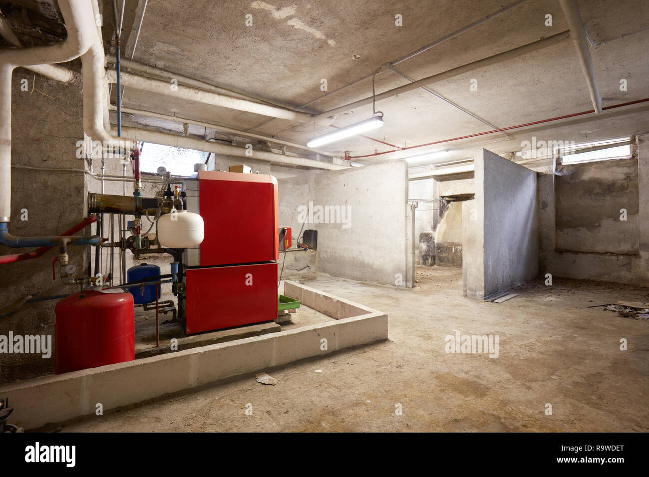 Basement with red heating boiler and dirty floor in old house interior Stock Photo