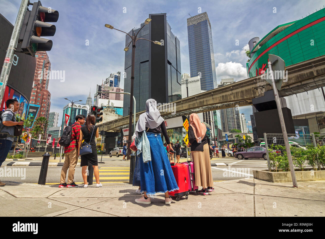 Kuala Lumpur, Malaysia Nov 10 2018 - Muslim Tourist with hijab carrying luggage waiting at the traffic light of famous junction of the shopping distri Stock Photo