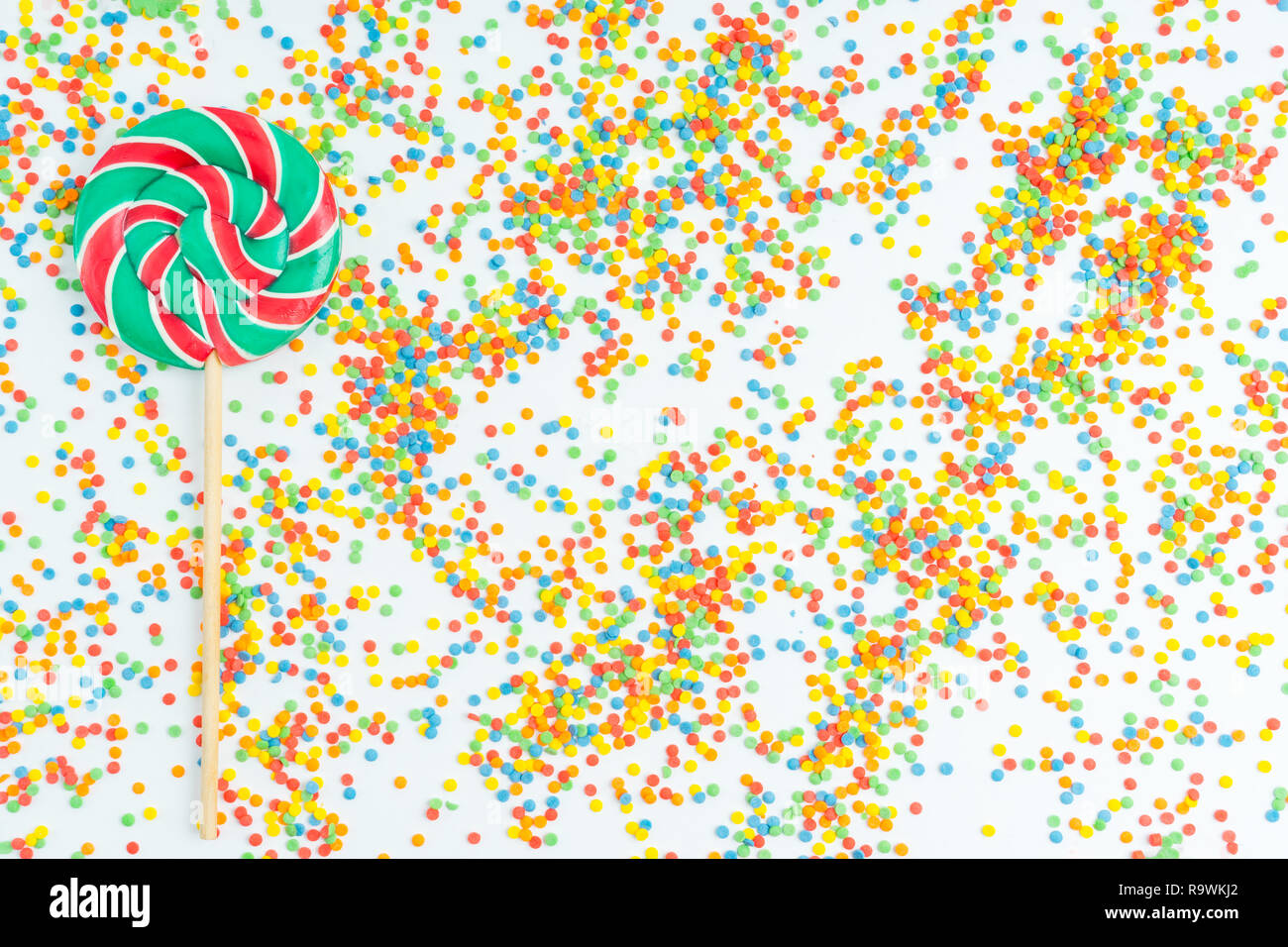 Colorful sweet candy on background of colorful confetti Stock Photo - Alamy