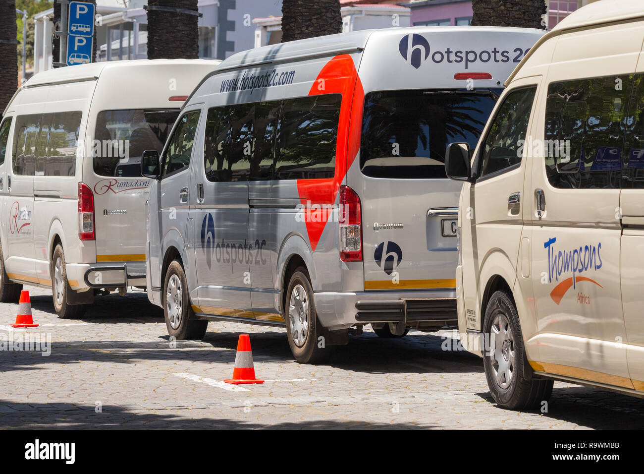 company tour or touring vehicles lined up behind plastic cones and parked in a tour bus area in a public car park in Cape Town, South Africa Stock Photo