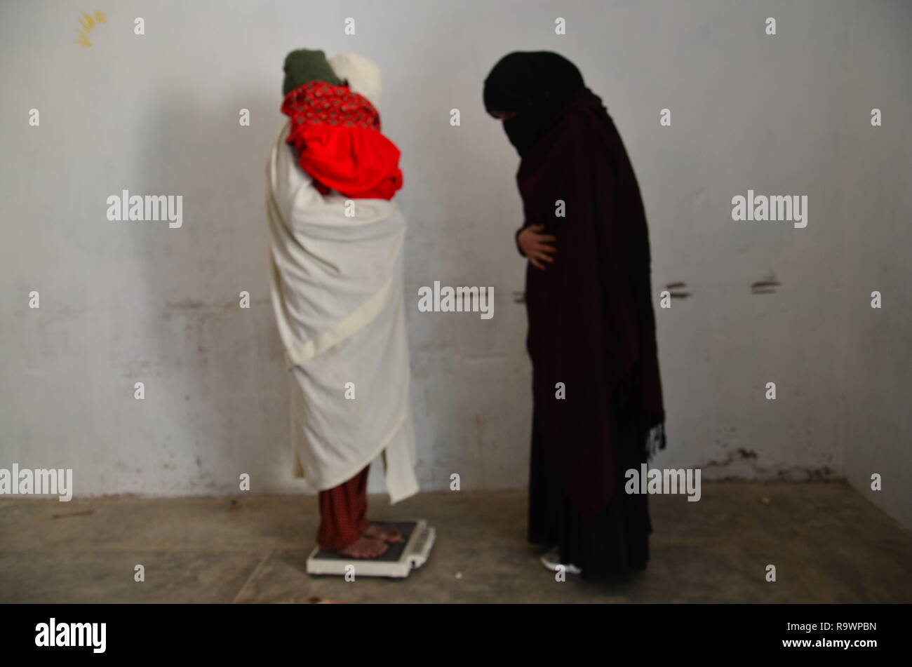 A lady health visitor checks weight of a mother in a basic health unit in Pakistan Stock Photo